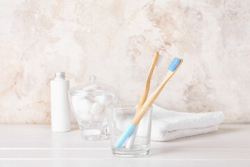 Fototapeta na wymiar Glass with wooden toothbrushes on white wooden table
