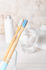 Fototapeta na wymiar Glass with wooden toothbrushes on white wooden table, closeup