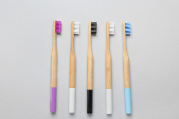 Different wooden toothbrushes on grey background