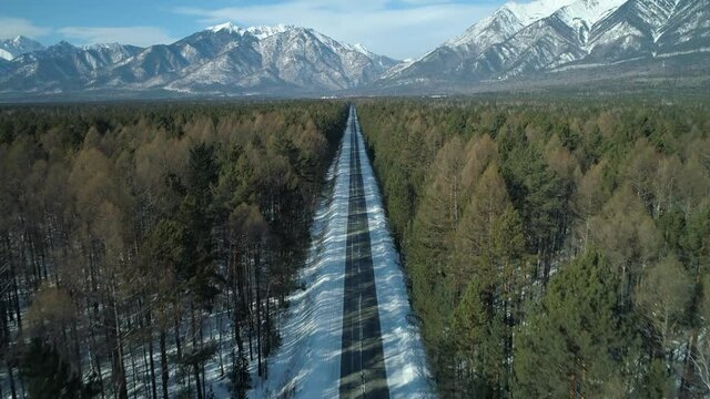 Bird&rsquo;s eye view Scenic straight road asphalt highway path among spruce pine forest. Buryatia epic winter snow-capped mountains Arshan. Tunkinsky nature reserve park. Baikal territory Siberia landmark