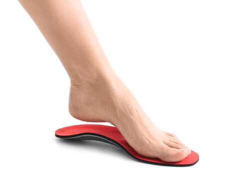 Female foot and red orthopedic insole on white background