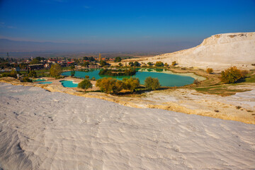 Fototapeta na wymiar PAMUKKALE, TURKEY: Landscape with a view of a pond in a Natural Park and white travertine on a sunny day in Pamukkale.