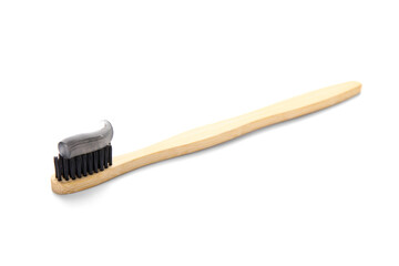 Bamboo brush with black tooth paste on white background
