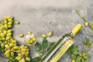 Top view of bottle white wine, green vine, wineglass and ripe grape on vintage gray stone table...