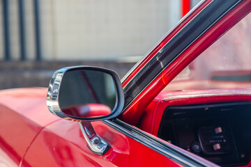 The vehicle's wing mirror of a red classic car or Muscle car