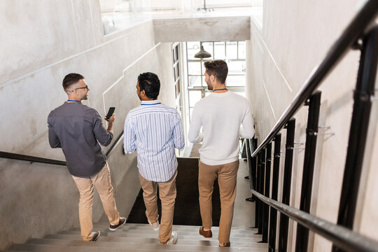 Business, People And Corporate Concept - Group Of Men Walking Down Office Stairs And Talking