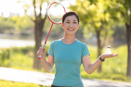 Happy mature woman playing badminton outdoors
