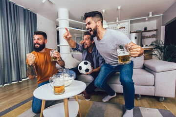 Very excited friends having fun by watching football match at home, indoors. Friendship,...