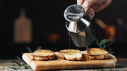 hand pours olive oil on toast bread