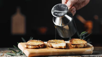 Fototapeten hand pours olive oil on toast bread © francescosgura