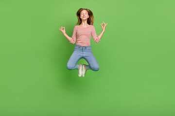 Photo of peaceful serene calm lady jump enjoy meditation practice wear striped shirt isolated green...