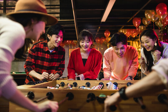 Happy young friends playing table football