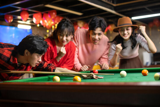 Happy young friends playing billiard together