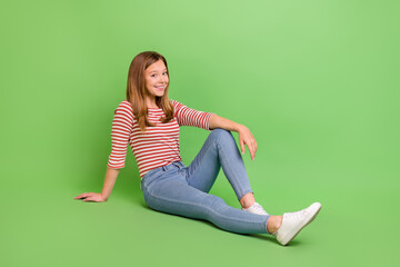 Photo of positive nice pretty lady sit floor enjoy rest wear striped shirt jeans isolated green color background