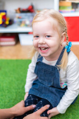 Woman speech therapist helps little girl to correct her speech in her office