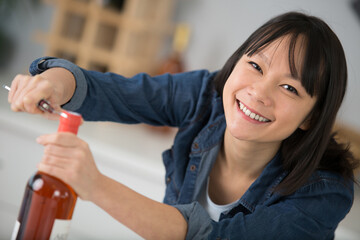 happy woman opens a wine bottle