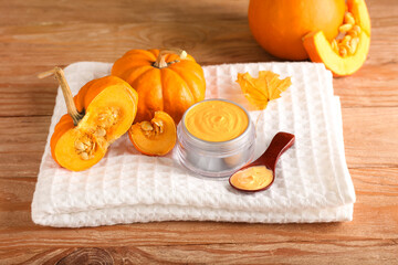 Jar of natural mask, pumpkins and towel on wooden background