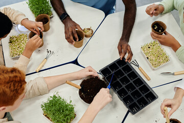 Top view close up of children planting seeds while experimenting at biology class in school