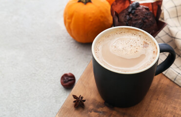 Cup of delicious pumpkin coffee on light background
