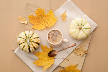 Cup of tasty pumpkin coffee on beige wooden background