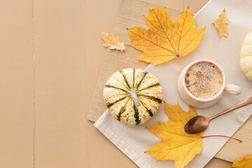 Cup of tasty pumpkin coffee on beige wooden background