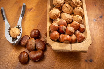 hazelnuts walnuts and chestnuts on a wooden table with  a nutcracker