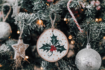 Close-up photo of a hand painted wooden christmas ornament with holly leaves