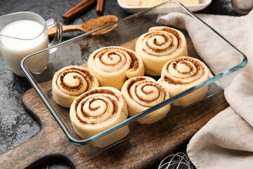 Baking dish with uncooked cinnamon rolls and on black background