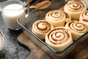 Baking dish with uncooked cinnamon rolls and on black background, closeup