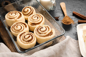 Baking dish with uncooked cinnamon rolls and on black background