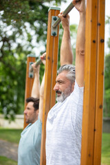two confident sportsmen outdoors doing bars