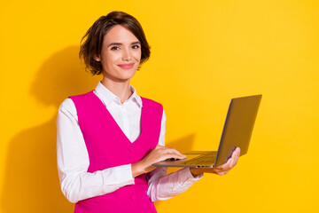 Photo of charming sweet young lady wear pink suit holding modern device smiling isolated yellow...