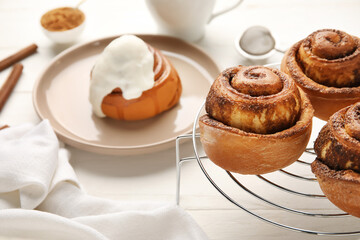 Grid with tasty cinnamon rolls on white wooden background, closeup