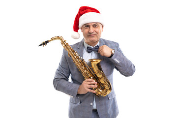 Sceptical man wears in Santa's hat holds saxophone while straightening bow tie on studio background
