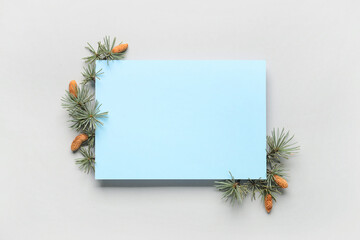 Blank card and fir branches with cones on white background