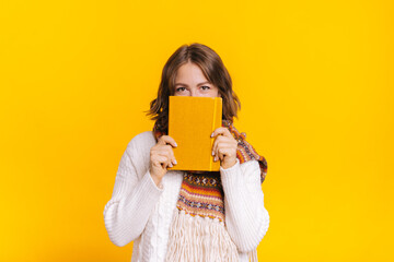 Young female in sweater holding orange agenda or planner - Powered by Adobe