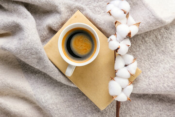 Cotton flowers, warm scarf, book and cup of coffee on light background