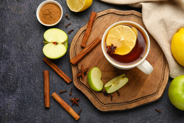 Cup of tasty fruit tea with cinnamon on black background