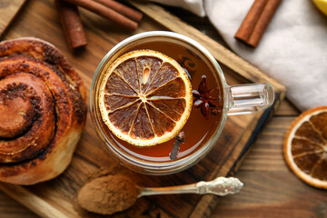 Glass cup of tasty orange tea with cinnamon on wooden background, closeup