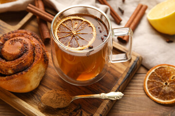 Glass cup of tasty orange tea with cinnamon on wooden background