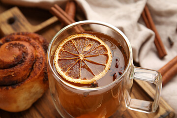 Glass cup of tasty orange tea with cinnamon on wooden background