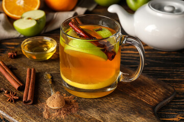 Glass cup of tasty fruit tea with cinnamon on wooden background