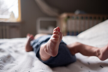 Charming legs of a newborn baby close-up lying on the bed in the bedroom