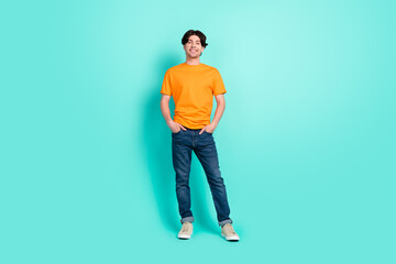 Fototapeta na wymiar Full size photo of funny brown hair young guy stand wear t-shirt jeans sneakers isolated on blue background