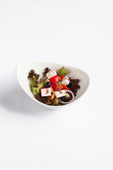 Greek salad in a plate. On white background.