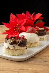 Top view of three chocolate and cheese nougat tartlets with quince, on wooden table, selective focus, with poinsettias, vertical