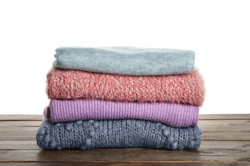 Obraz na płótnie Canvas Stack of warm soft sweaters on wooden table against white background