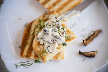 fried bread toast with cheese spread with boiled dried mushrooms on a wooden table.