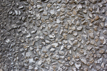 Gray Cement wall background textured with stone chips. Concrete wall of a building with stones of different sizes, close-up view