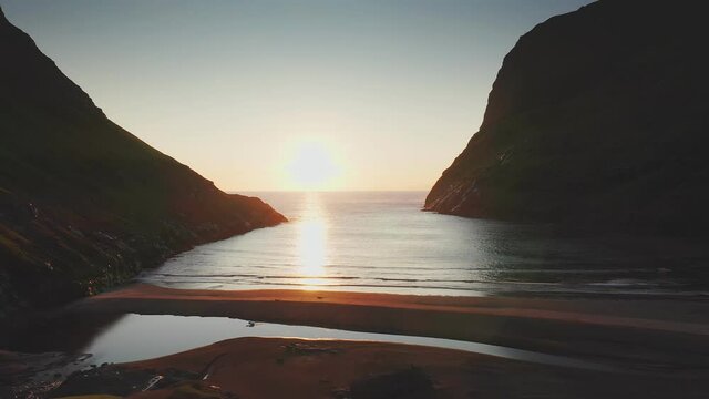 Aerial view of sunset on the beach with awesome sun golden reflection on calm waves. Golden beach and mountain silhouette in both side.Unusual landscape and backgrounds, Faroe islands